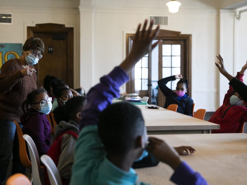 Students raise their hands during a discussion of poetry at the 1619 Freedom School.