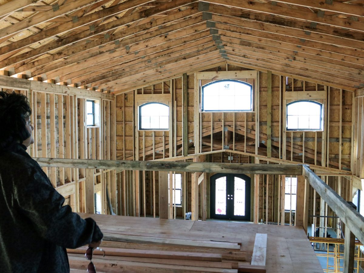 Teresa Rutherford gazes at her under-construction house from the second level. It's the wooden bones of the home, with light streaming in the windows.