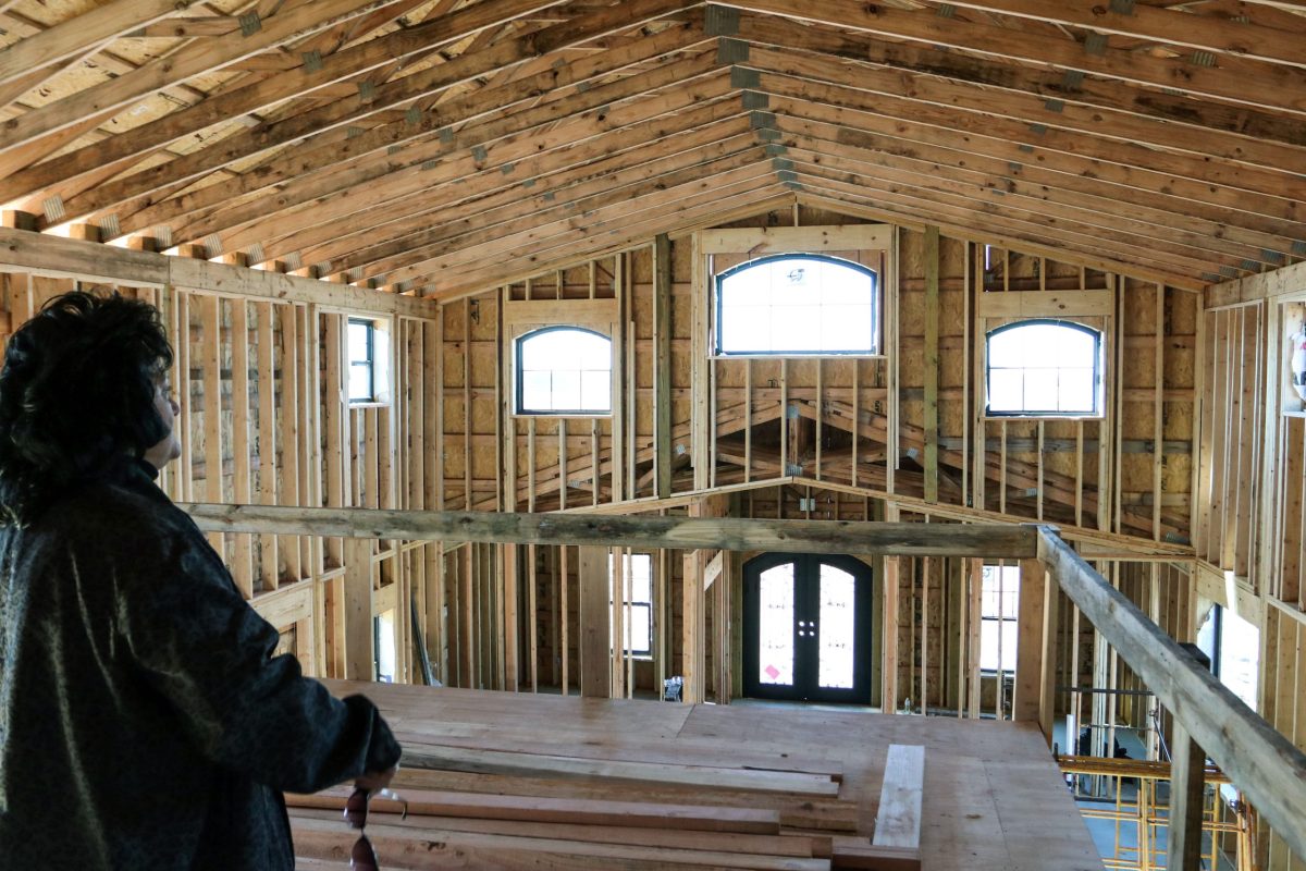 Teresa Rutherford gazes at her under-construction house from the second level. It's the wooden bones of the home, with light streaming in the windows.