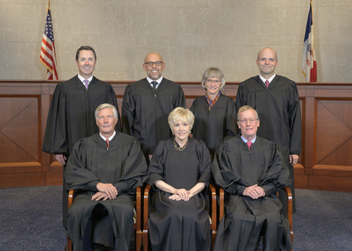 The seven Iowa Supreme Court justices pose for a group photo, all dressed in their judicial robes.