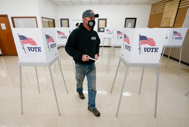 Chris Helps, of Earlham, Iowa, makes his way to the ballot box at a polling place during early voting.