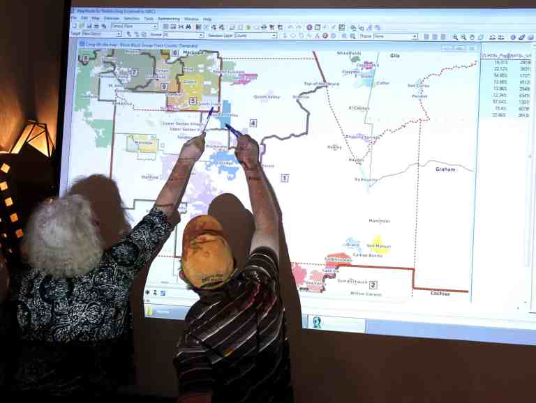 Commission attorney Mary O'Grady speaks with a Casa Grande city council member as they point to a possible map outlining the new congressional landscape during an Arizona redistricting meeting.