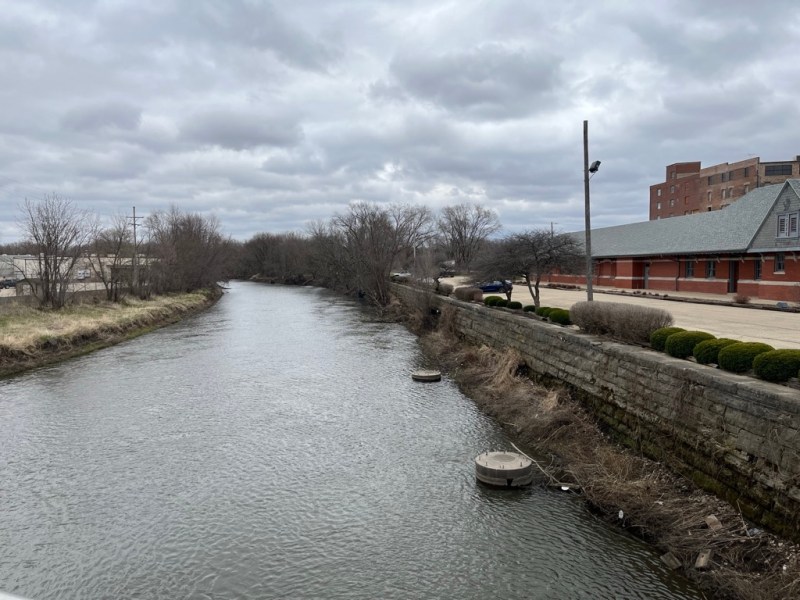 A view of the Pecatonica River. On both sides there are buildings near the river's edge.