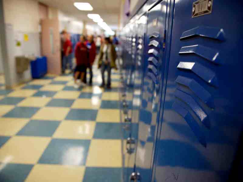 A look at a school hallway as students gather around lockers.