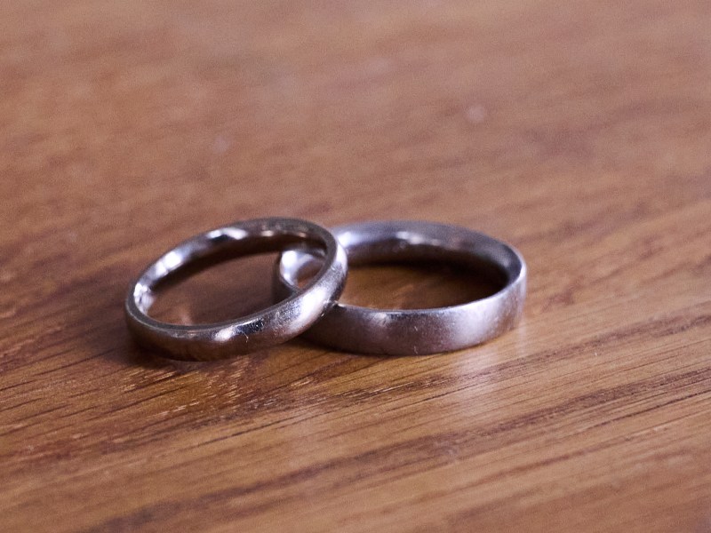 Two silver wedding rings lie next to each other on a wooden table.