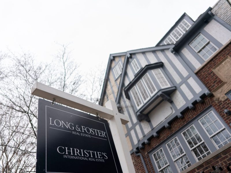 A Long and Foster and Christie's real estate sign hangs in front of a home.