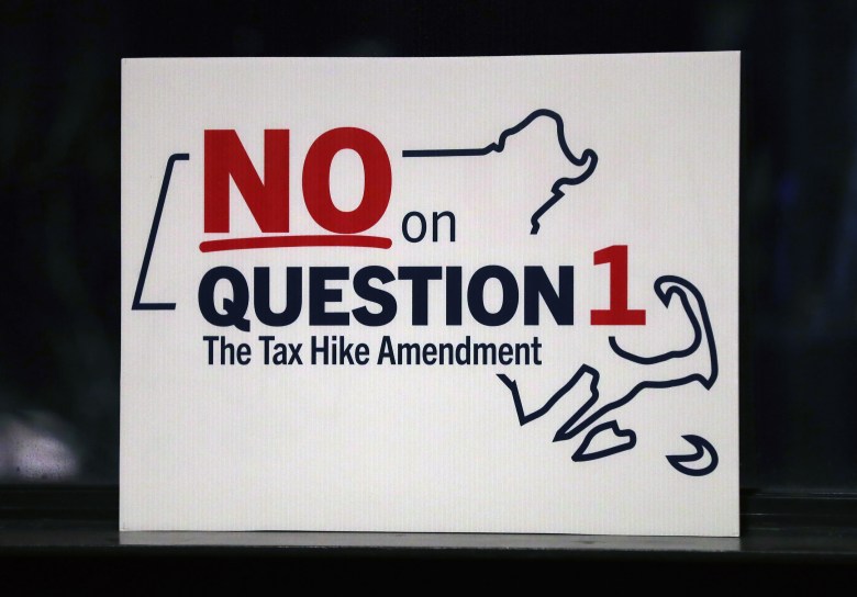 A sign says, "NO on Question 1 the Tax Hike Amendment," over a drawing of the state