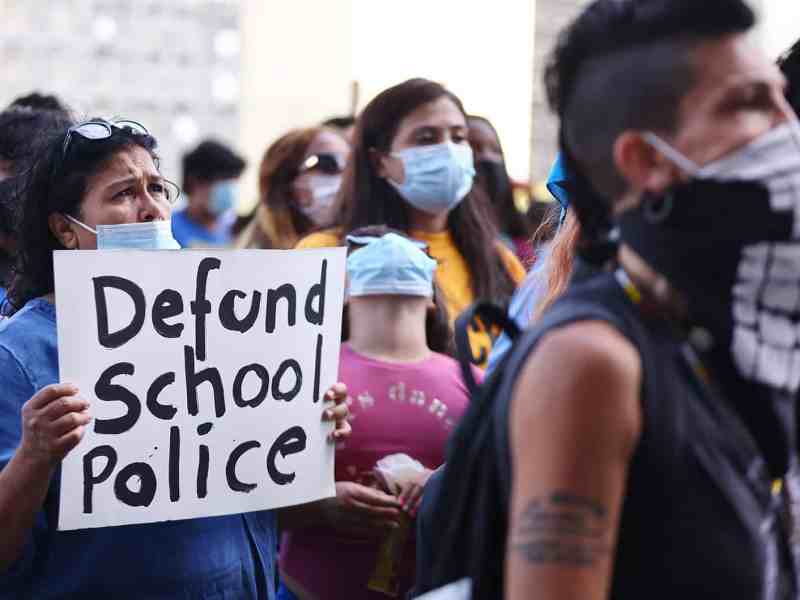 A protester holds up a sign that says 'defund school police' outside the Unified School District headquarters in Los Angeles.