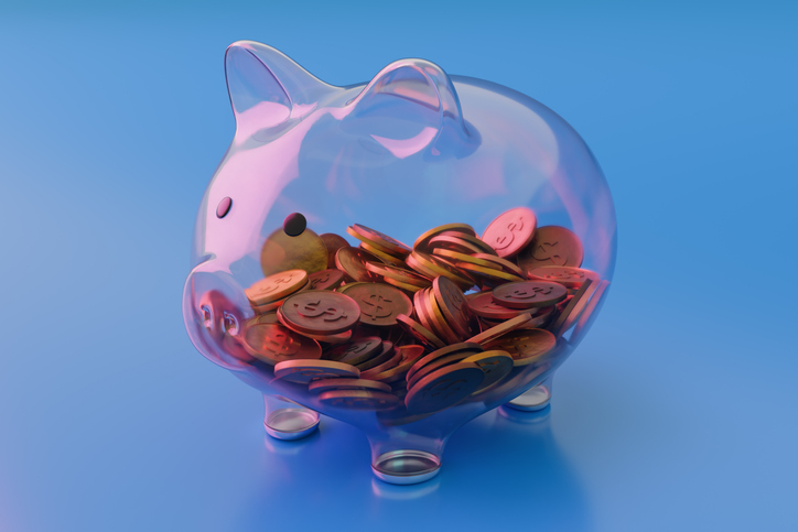 See Through Transparent Glass Piggy Bank With Coins on Blue Background