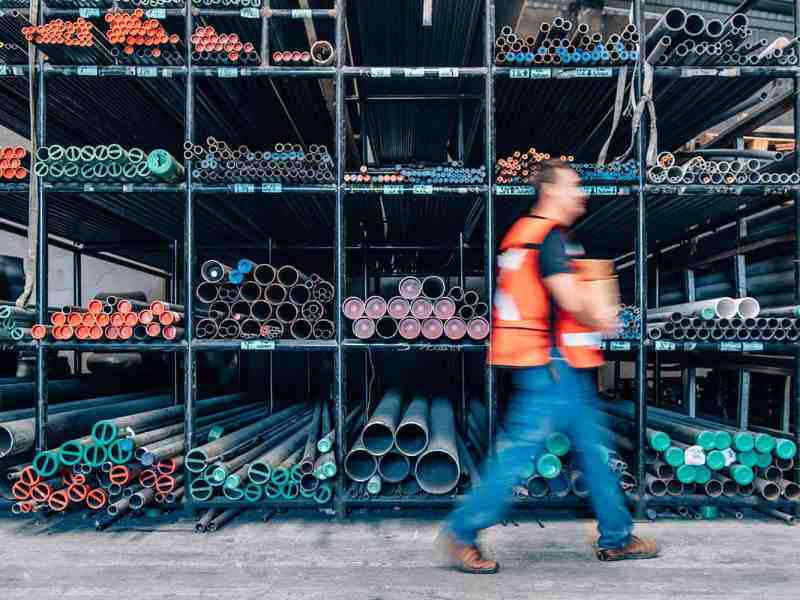 A person walks past pipes at a warehouse.