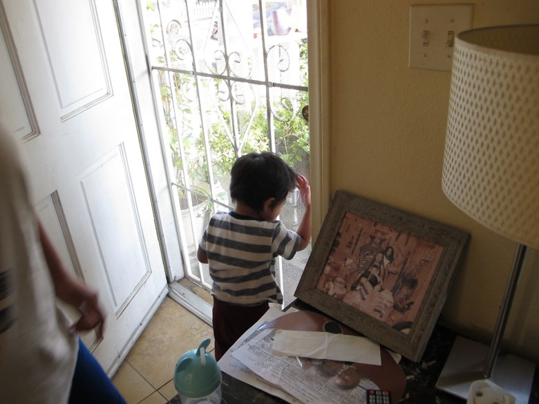 Two-year-old Niallel cries as he looks out of the screen door of his home.