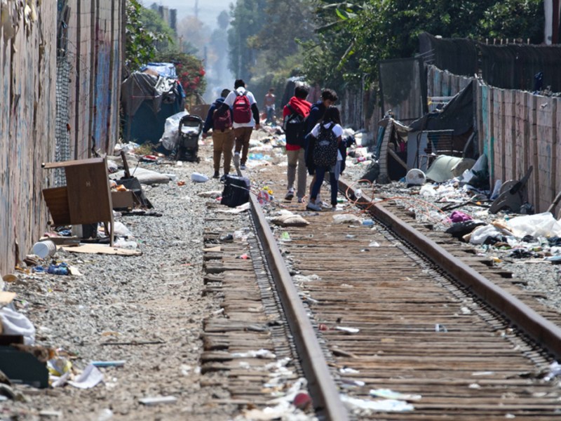 Santa Ana children walk along the train tracks that are littered with debris.