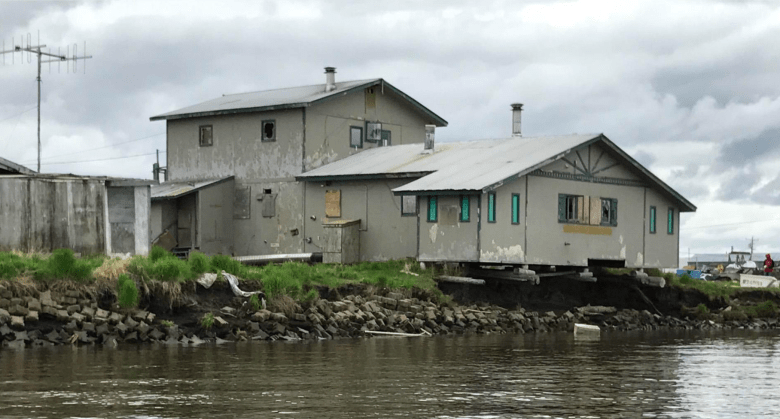Homes are built right on the edge of a riverbank. Part of the house hangs over the river with steel planks holding it up over the river.